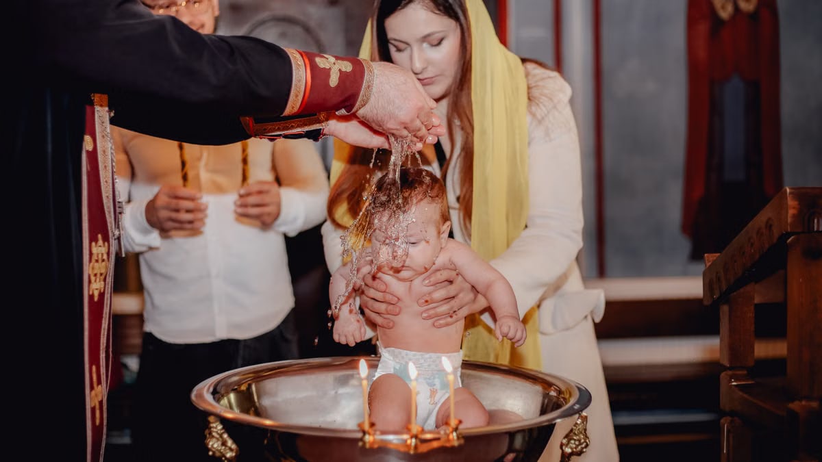A traditional baby baptism ceremony inside a church with priest and family present.