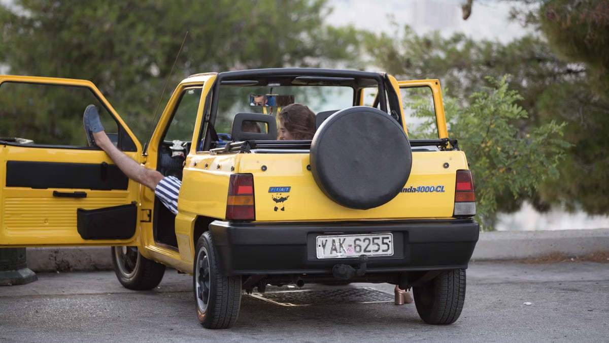 Relaxed scene featuring a vintage Fiat Panda with open doors in a scenic outdoor setting.